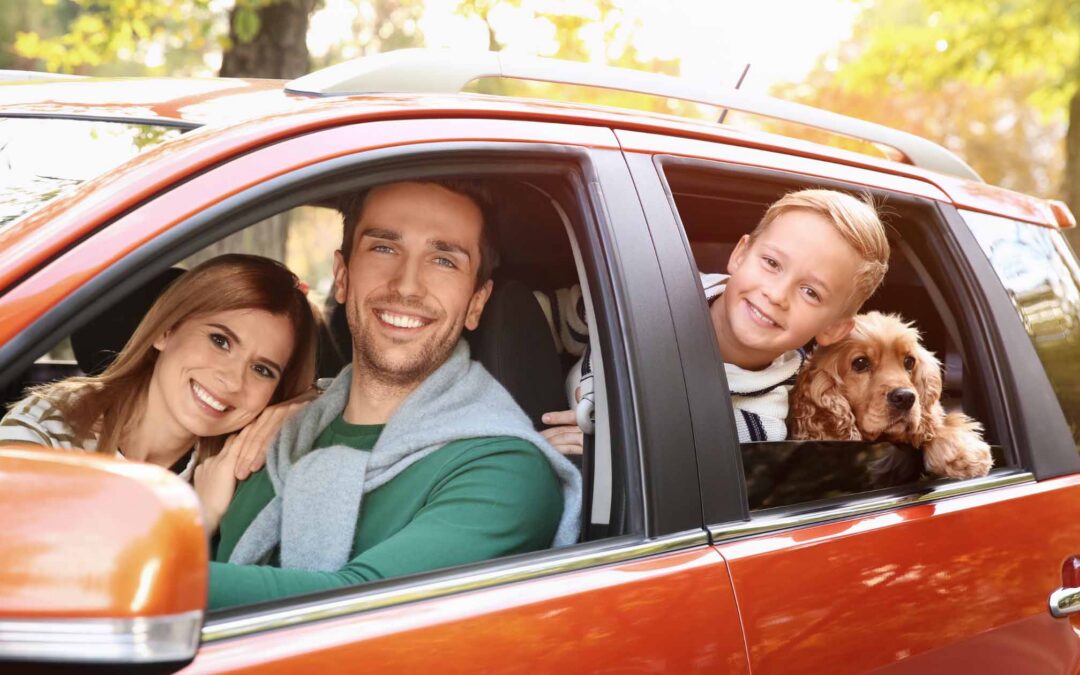 Happy family riding a car with pet dog